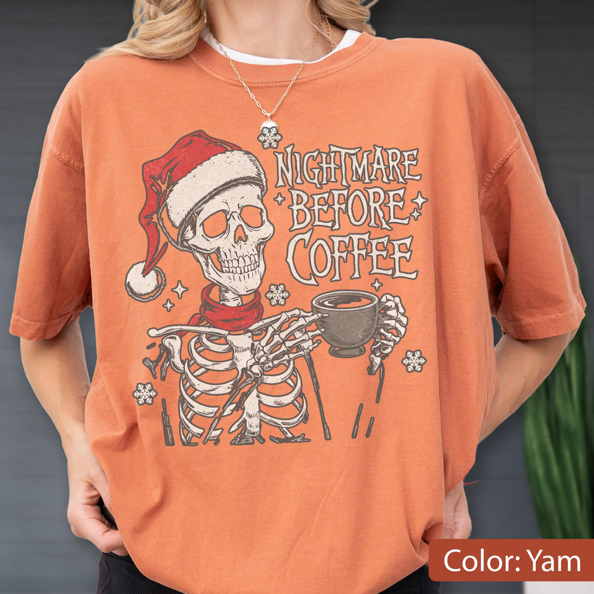 May include: Orange-colored t-shirt with a graphic of a skeleton wearing a Santa hat and scarf, holding a coffee cup. The text reads "Nightmare Before Coffee". The shirt has short sleeves and a crew neck.