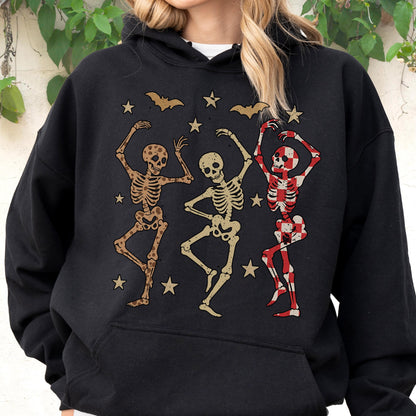 May include: Black hoodie featuring a graphic of three dancing skeletons in shades of brown and red, with stars and bats. The skeletons have different patterns and colors. A fun and festive design for Halloween or a themed event.