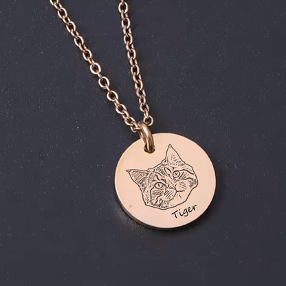 May include: A rose gold necklace featuring a circular pendant with an engraved cat portrait. The word "Tiger" is written below the cat's face. The chain is delicate and the pendant is round.