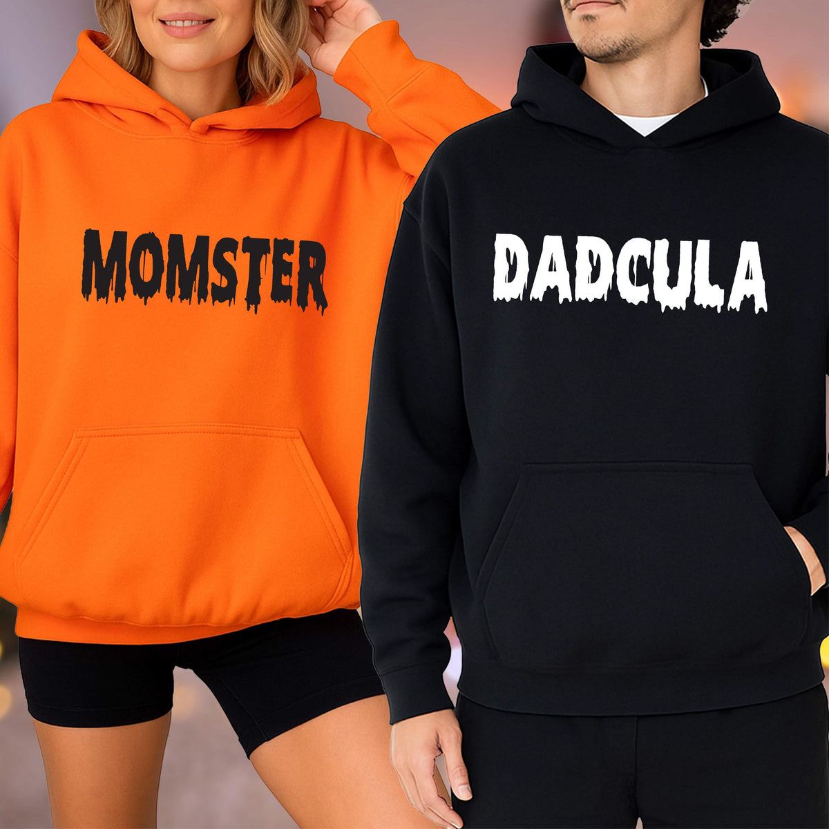 May include: Two hooded sweatshirts, one orange and one black. The orange sweatshirt has the word "MOMSTER" printed in black, and the black sweatshirt has the word "DADcula" printed in white. Both sweatshirts have a front pocket and a hood.