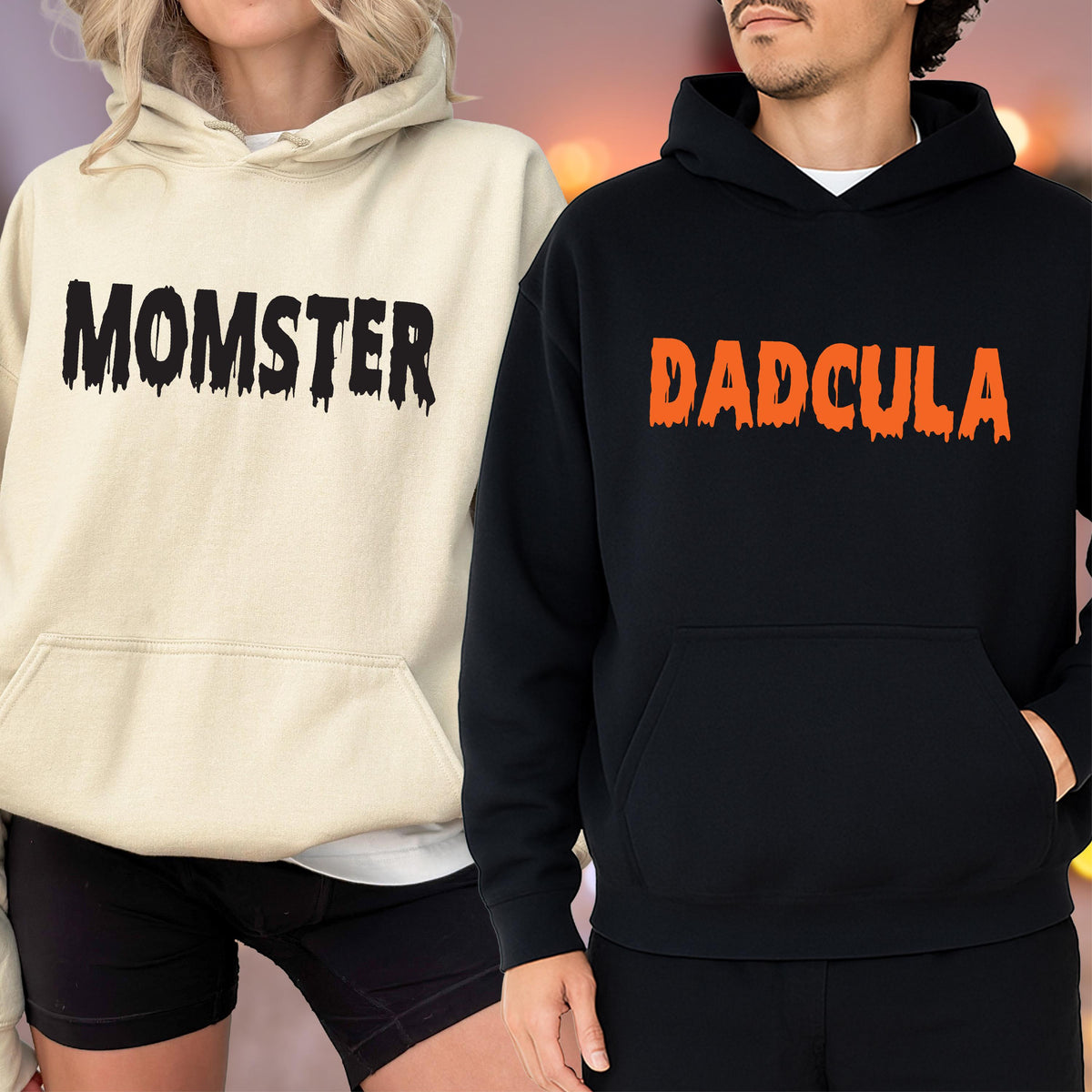 May include: Two hooded sweatshirts, one cream-colored and one black. The cream-colored sweatshirt has the word "MOMSTER" in black dripping font. The black sweatshirt has the word "DADcula" in orange dripping font. Both sweatshirts have a front pocket.