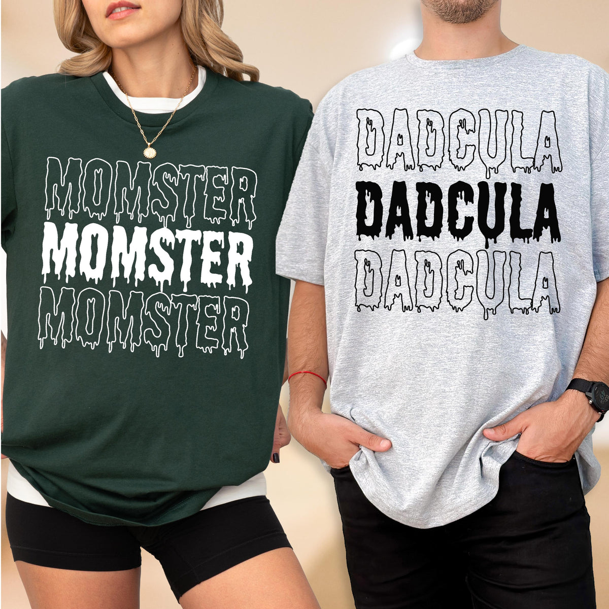 May include: Two t-shirts, one dark green and one gray, with Halloween-themed text. The dark green shirt says "MOMSTER" in white, dripping font. The gray shirt says "DADcula" in a similar font. Both shirts have a white collar.