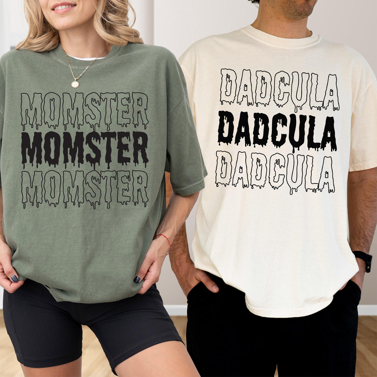 May include: Two t-shirts, one olive green and one cream, each with a Halloween-themed graphic. The olive green shirt says "MOMSTER" three times in a dripping font. The cream shirt says "DADcula" three times in a dripping font.