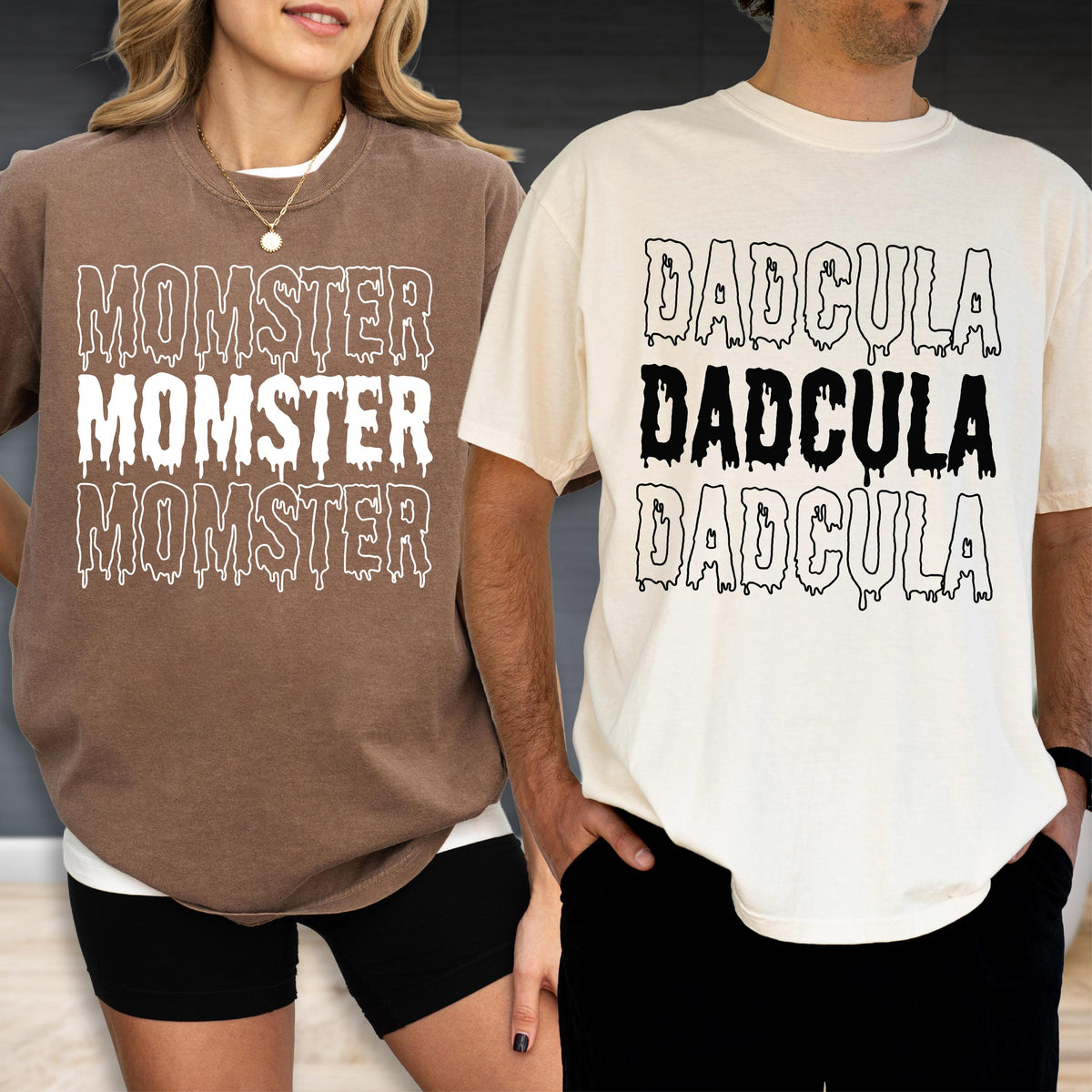 May include: Two t-shirts, one brown and one cream, each with a unique graphic. The brown shirt says "MOMSTER" three times in a dripping font. The cream shirt says "DADCULA" three times in a dripping font.