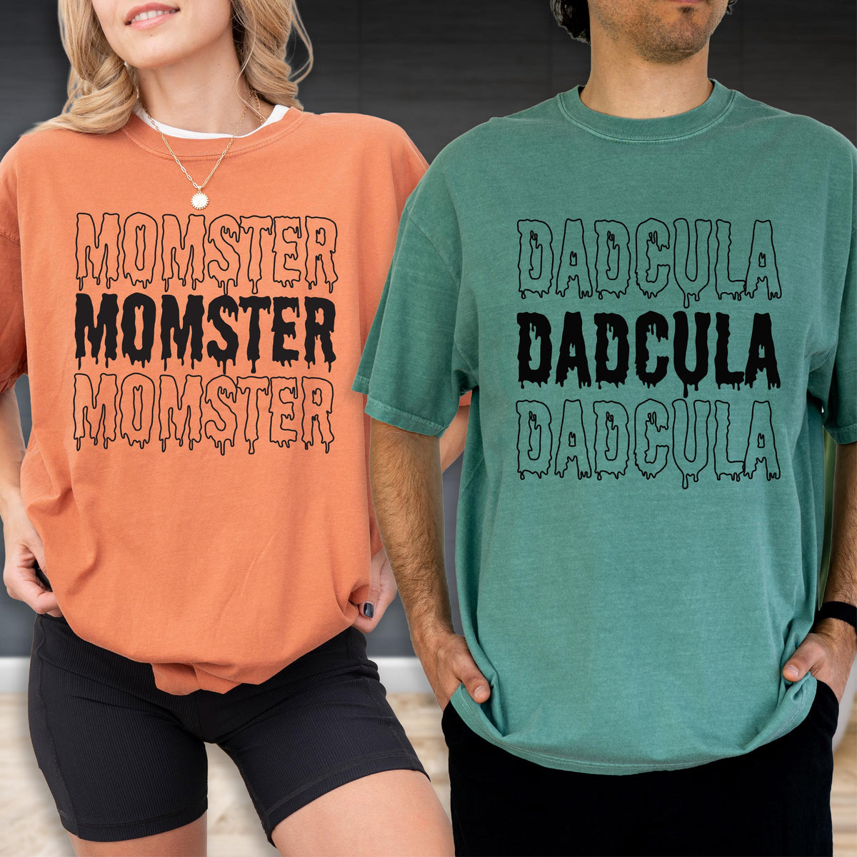 May include: Two t-shirts, one orange and one teal, each with a unique graphic. The orange shirt says "MOMSTER" three times in a dripping font. The teal shirt says "DADcula" three times in a similar font. Both shirts are short-sleeved.
