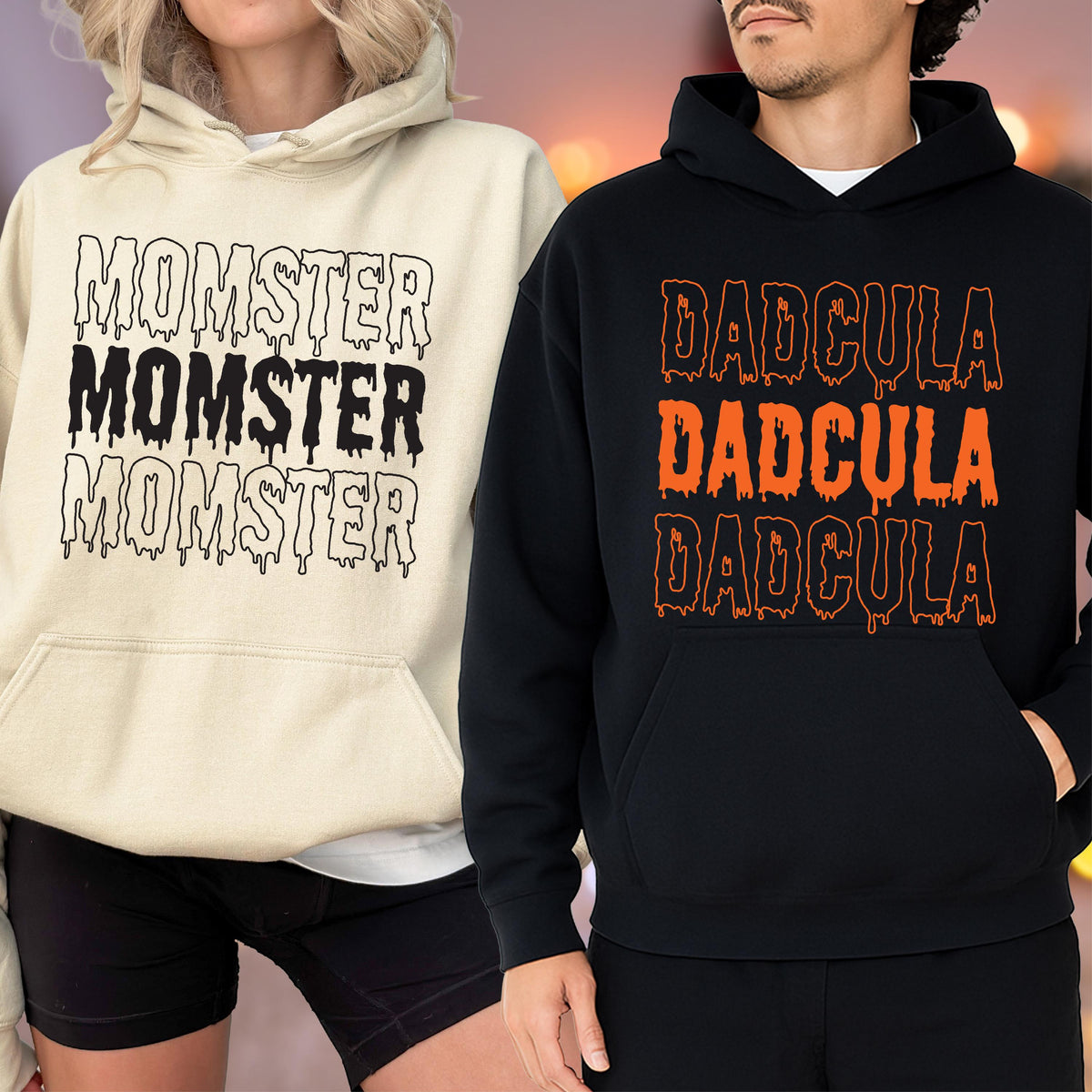 May include: Two hooded sweatshirts, one cream-colored and one black. The cream sweatshirt has the word "MOMSTER" printed three times in a dripping font. The black sweatshirt has the word "DADCULA" printed three times in an orange dripping font.