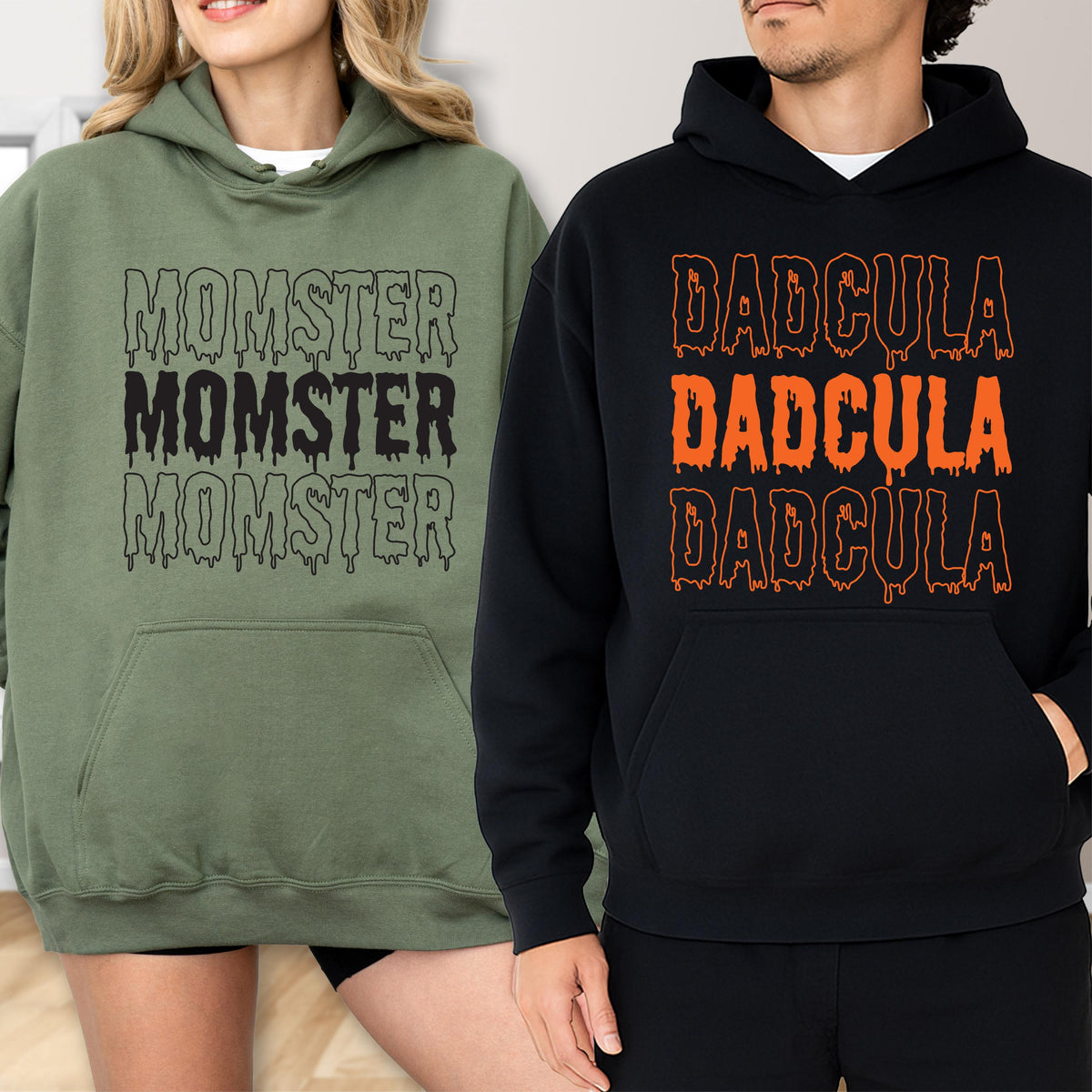 May include: Two hooded sweatshirts, one olive green and one black. The olive green sweatshirt has the word "MOMSTER" printed three times in black. The black sweatshirt has the word "DADcula" printed three times in orange.
