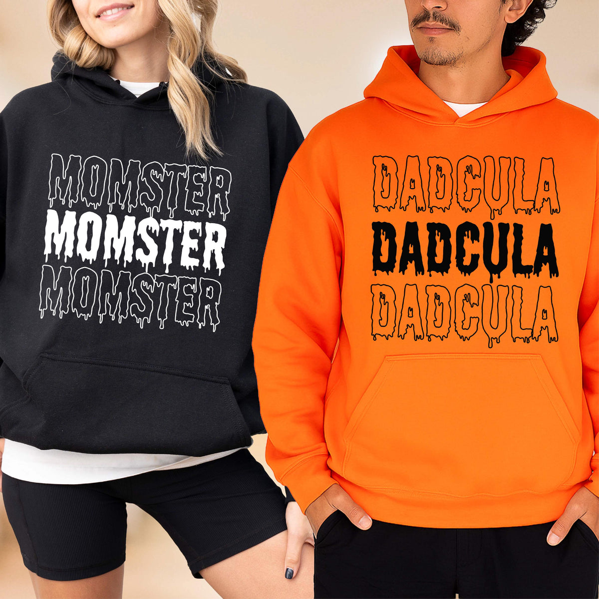 May include: Black and orange hoodies with the words "MOMSTER" and "DADcula" in a dripping font. The black hoodie is worn by a person on the left, and the orange hoodie is worn by a person on the right. Both hoodies have a front pocket and a hood.
