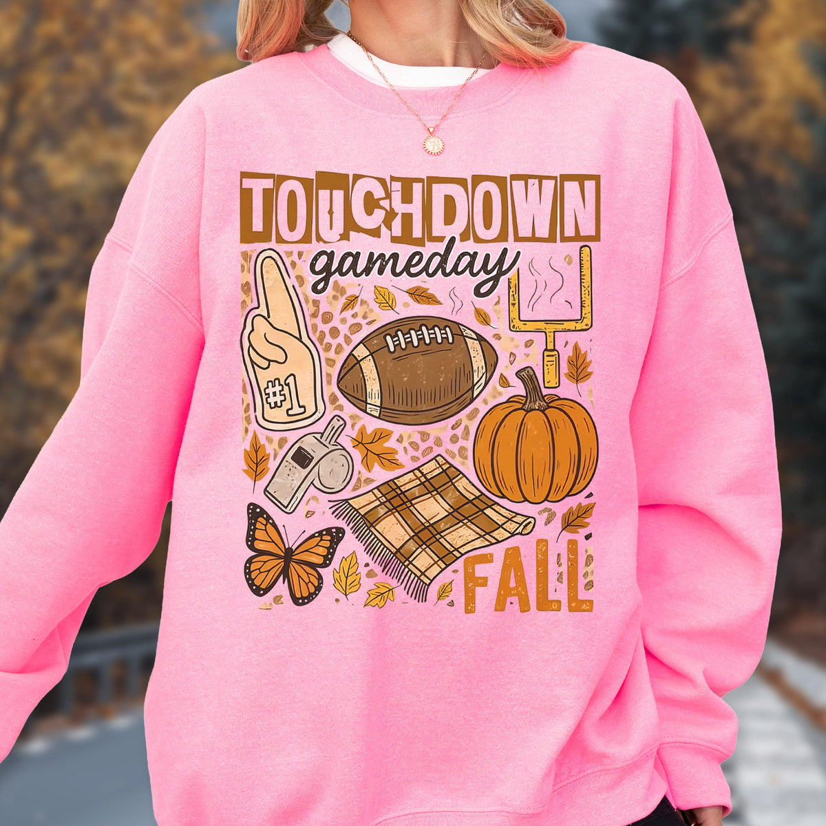 May include: Pink sweatshirt with a graphic design featuring the words "TOUCHDOWN gameday FALL". The design includes a football, pumpkin, foam finger, whistle, butterfly, and a plaid blanket.