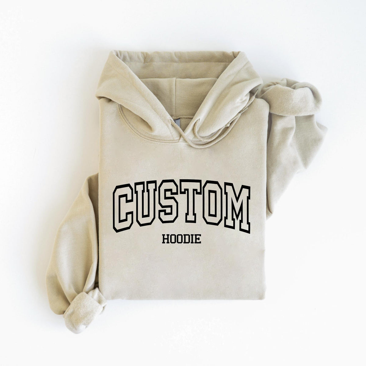 May include: A beige hoodie with the word "CUSTOM" in bold, black, collegiate-style lettering across the chest. Below the word "CUSTOM" is the word "HOODIE" in a smaller font. The hoodie has a hood and long sleeves.