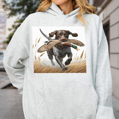 May include: A light gray hoodie featuring a detailed illustration of a hunting dog running through tall grass with a duck in its mouth. The dog is brown and white with floppy ears. The duck has brown and green feathers.