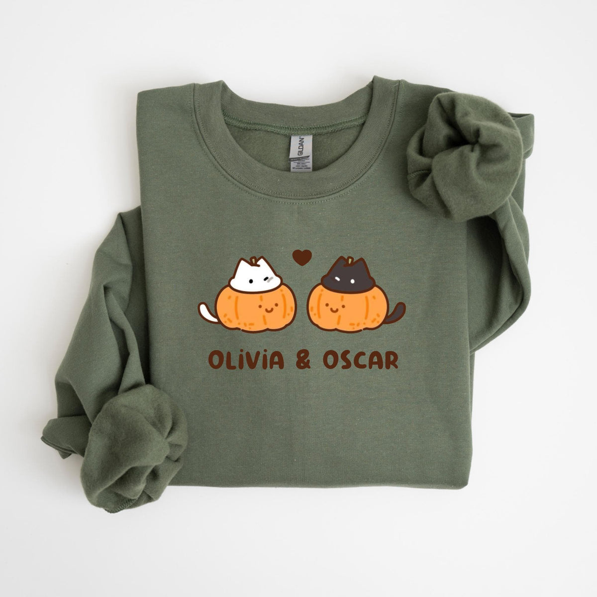 May include: Olive green sweatshirt featuring a graphic of two cats in pumpkin costumes with the text "OLIVIA & OSCAR" below. The cats are white and black, and the pumpkins are orange. A small brown heart is between the cats.