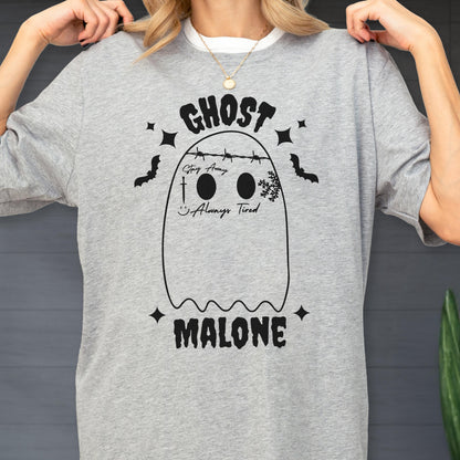 May include: A heather gray t-shirt featuring a black graphic of a ghost with barbed wire across its head, the text "GHOST MALONE," "Stay Away," and "Always Tired," along with a sword, a smiley face, a snowflake, bats, and four-pointed stars.