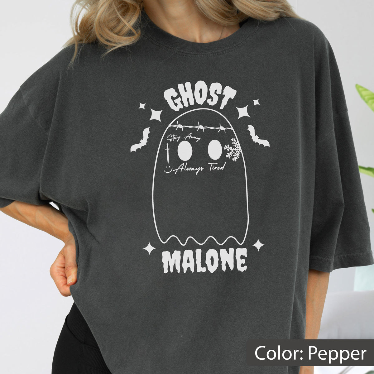 May include: Pepper-colored t-shirt with a white ghost graphic. The graphic includes the text "GHOST MALONE", a ghost outline, bats, and the phrases "Stay Away" and "Always Tired".
