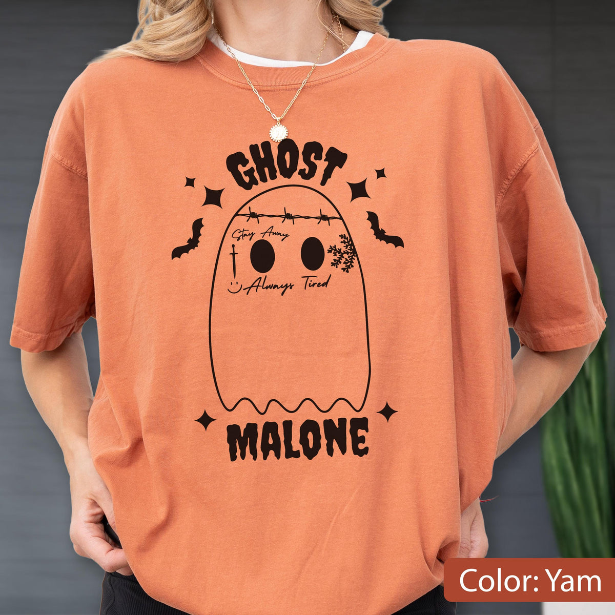 May include: Orange-colored t-shirt with a ghost graphic. The ghost design includes the text "GHOST MALONE" and the phrase "Always Tired". The shirt also features bats and stars.