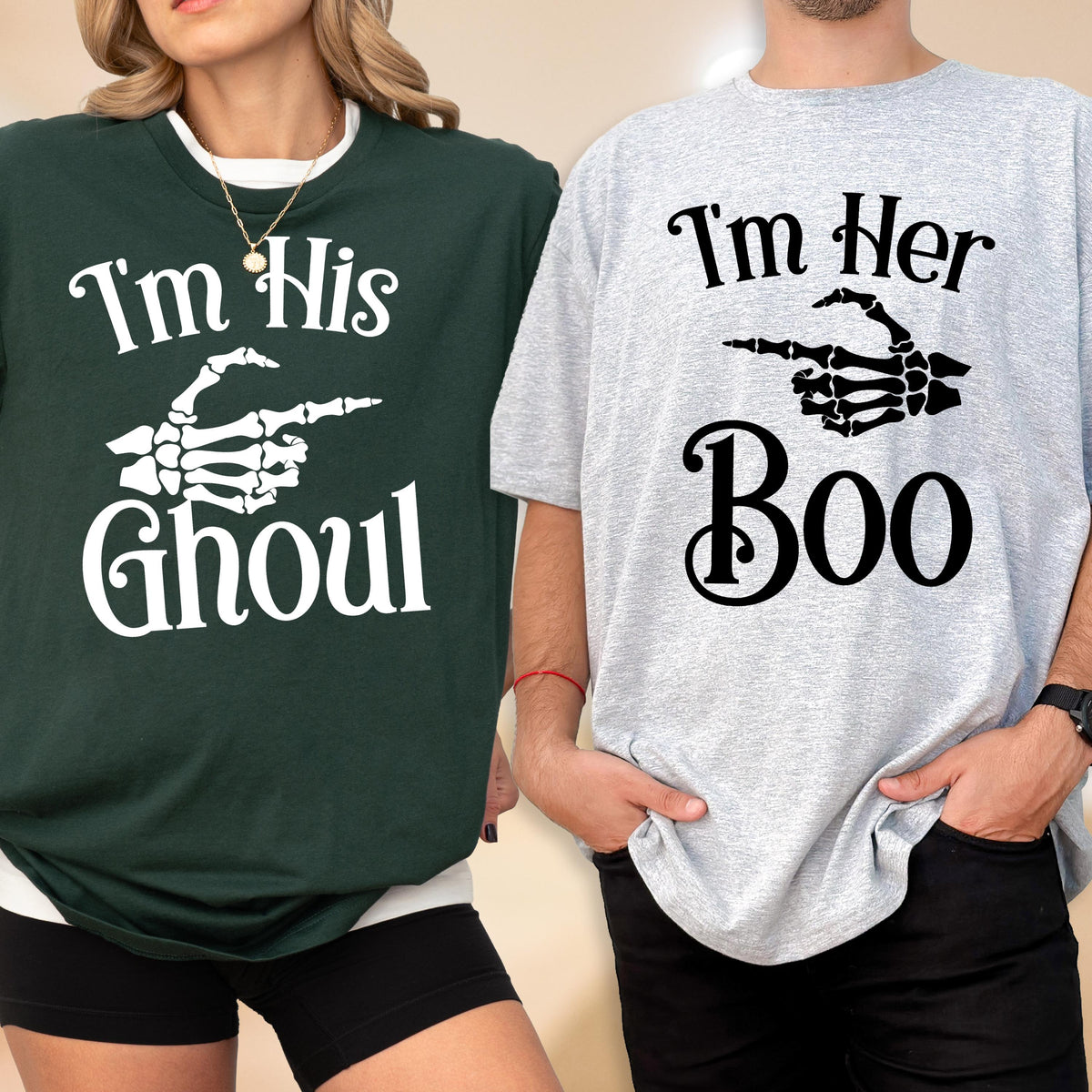 May include: A dark green t-shirt with white text reading I'm His Ghoul and a white skeleton hand graphic, paired with a light gray t-shirt with black text reading I'm Her Boo and a black skeleton hand graphic pointing to the side.