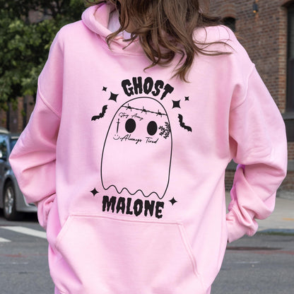 May include: A light pink hoodie with a front pocket and a drawstring hood. The back features a black ghost graphic with the words "GHOST MALONE" and the phrase "Stay Away Always Tired". Black bats and stars surround the ghost.