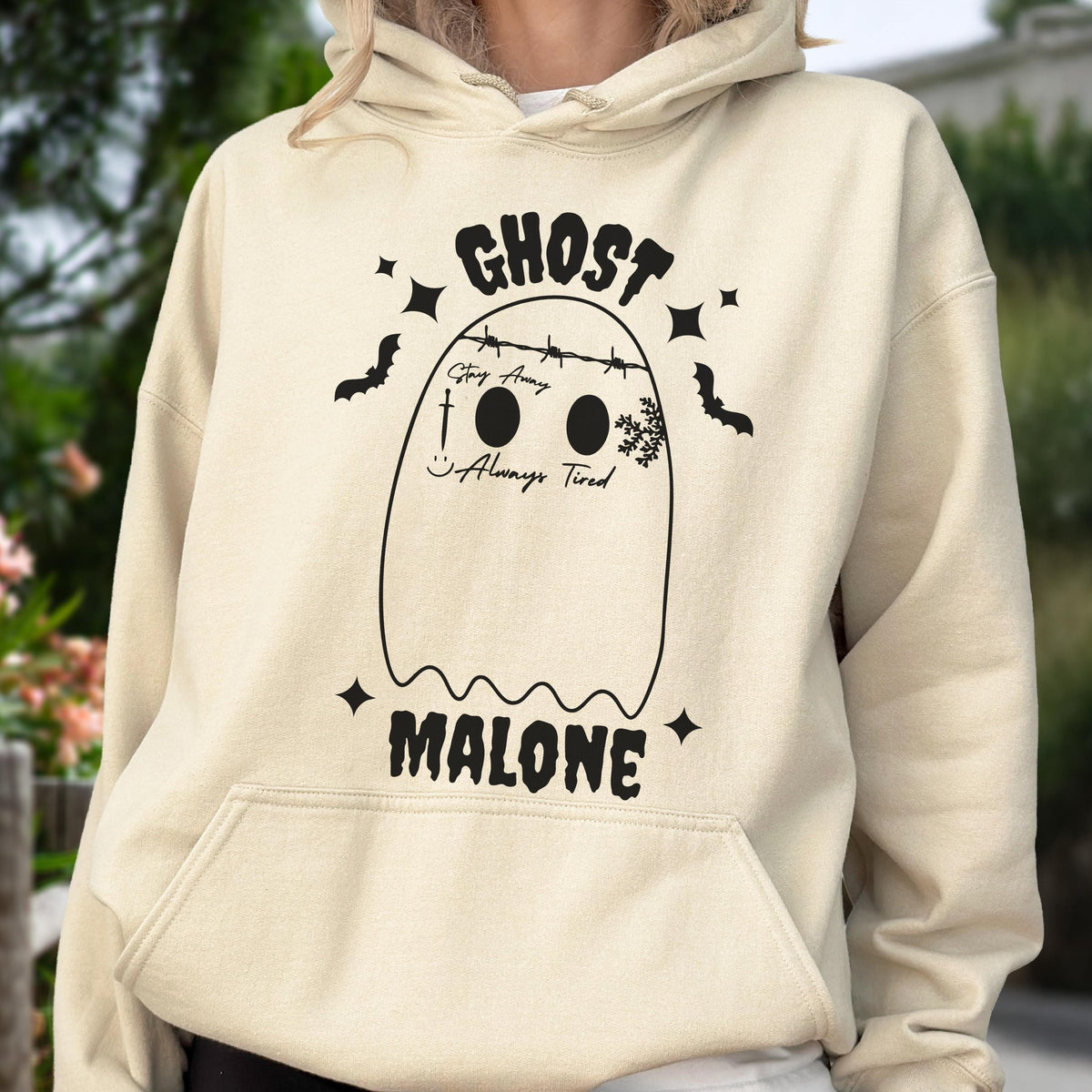 May include: A beige hoodie with a black graphic of a ghost with the text "GHOST" above it and "MALONE" below. The ghost design includes the text "Stay Away" and "Always Tired". Bats and stars surround the ghost.
