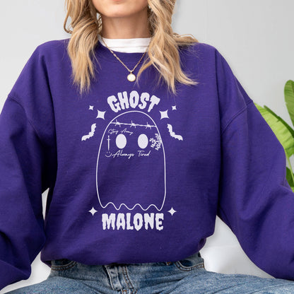 May include: A purple sweatshirt with a white ghost graphic. The ghost design includes the words "GHOST" and "MALONE", along with the phrases "Stay Away" and "Always Tired". The design also features bats, stars, and a snowflake.