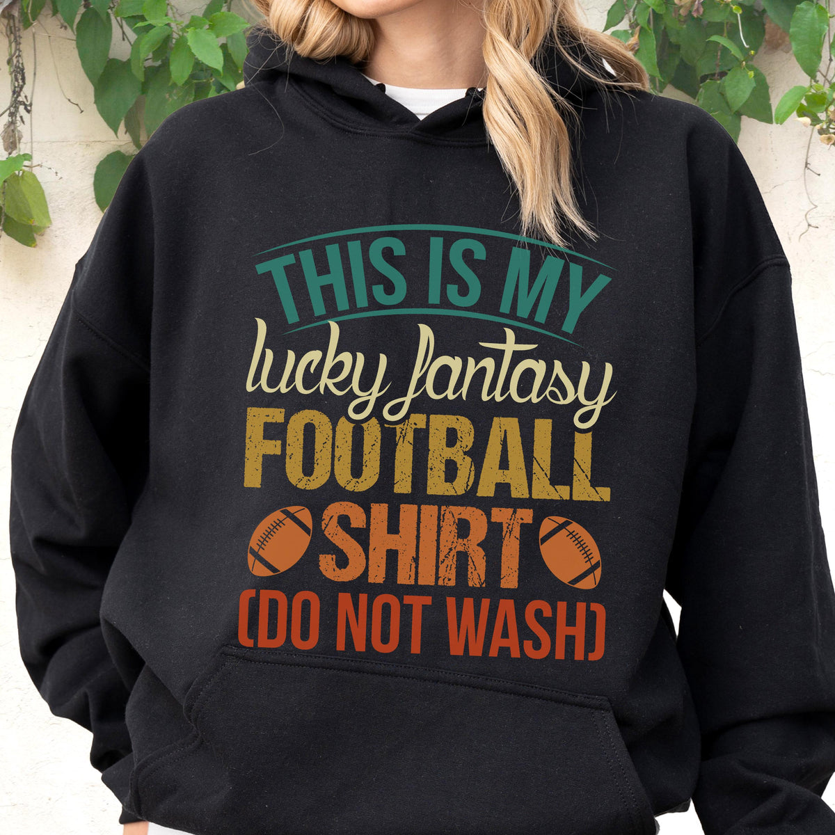 May include: Black hoodie with the text "THIS IS MY lucky fantasy FOOTBALL SHIRT (DO NOT WASH)". The text is in teal, yellow, orange, and white. Two orange footballs are also printed on the shirt.