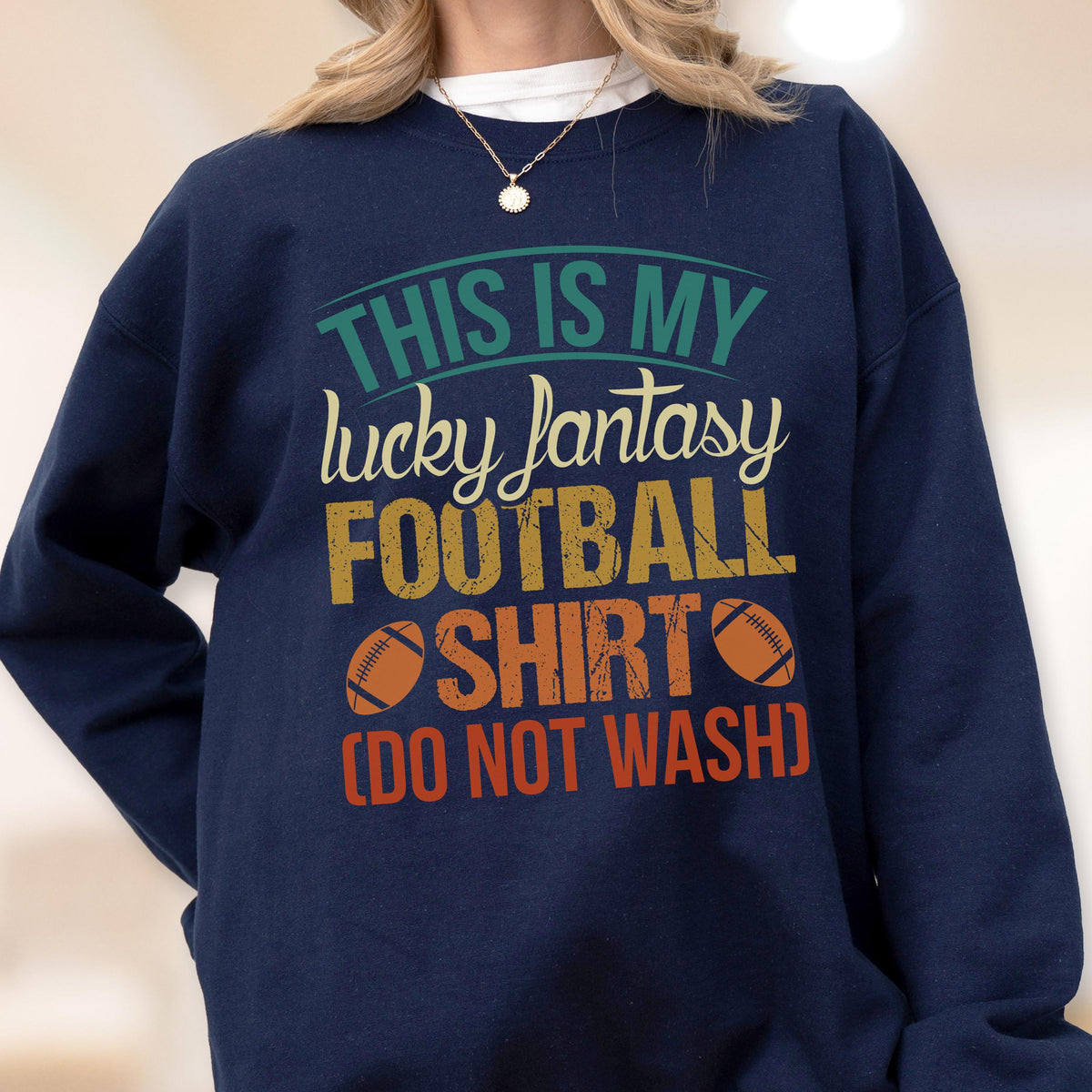 May include: Navy blue sweatshirt with the text "THIS IS MY lucky fantasy FOOTBALL SHIRT (DO NOT WASH)". The text is in teal, yellow, orange, and red. Two footballs are printed on the shirt.
