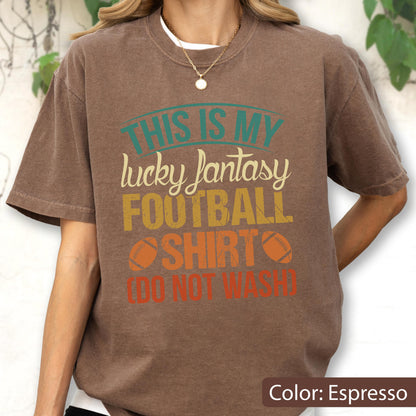 May include: An espresso brown short-sleeve t-shirt featuring the text "THIS IS MY lucky fantasy FOOTBALL SHIRT (DO NOT WASH)" in teal, cream, yellow, and orange, with two brown football graphics flanking the word "SHIRT" on the front.