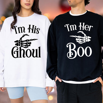 May include: Matching Halloween sweatshirts, one white and one black. The white sweatshirt says "I'm His Ghoul" with a skeleton hand pointing to the right. The black sweatshirt says "I'm Her Boo" with a skeleton hand pointing to the left. Both have a crew neck.