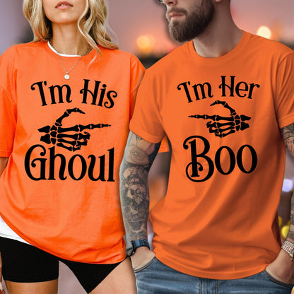 May include: Two bright orange t-shirts featuring black text and a skeleton hand graphic. The left shirt displays the text I'm His GHOUL with a skeleton hand pointing right. The right shirt displays the text I'm Her Boo with a skeleton hand pointing left.