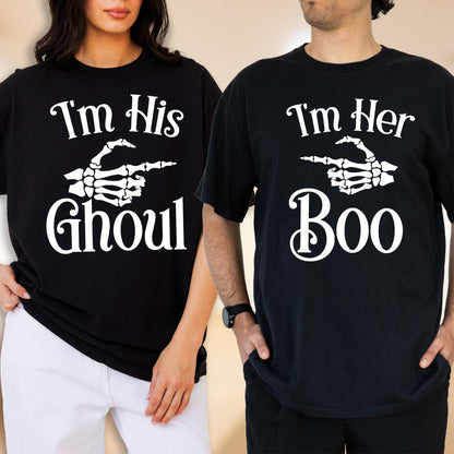 May include: Two black t-shirts with white screen-printed graphics. The left shirt features a skeleton hand pointing right with the text I'm His GHOUL. The right shirt features a skeleton hand pointing left with the text I'm Her Boo.