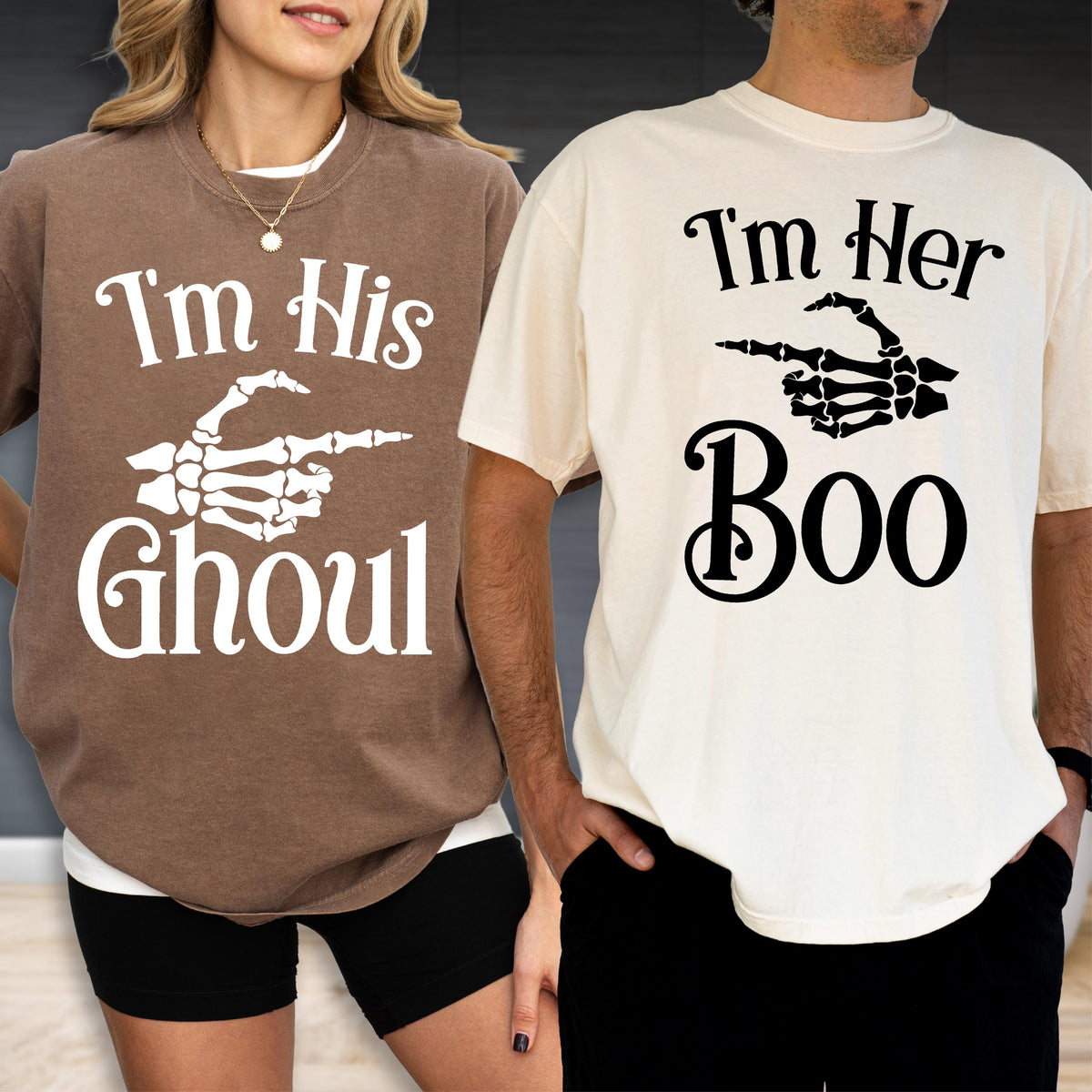 May include: A brown t-shirt with white text reading I'm His GHOUL and a white skeleton hand graphic, paired with a cream t-shirt with black text reading I'm Her Boo and a black skeleton hand graphic pointing to the side on both shirts.