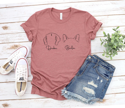May include: A pink t-shirt with a black outline of a dog and a cat on the front. The text 'Duke' is under the dog and 'Bella' is under the cat.