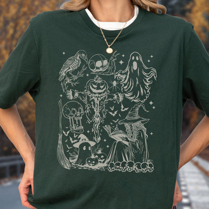 May include: Dark green t-shirt featuring a detailed, light gray Halloween-themed graphic. The design includes a crow, skulls, a jack-o'-lantern, a scarecrow, ghosts, bats, a witch reading a book, and other spooky elements. The shirt has a crew neck and short sleeves.