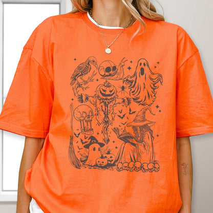 May include: Orange t-shirt with a black Halloween-themed graphic. The design includes a crow, skulls, a scarecrow, ghosts, bats, a witch reading a book, pumpkins, and a broom. The shirt is made of a soft material.