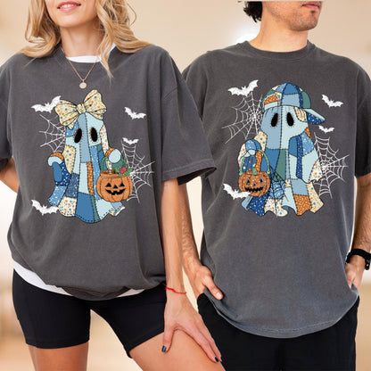 May include: Two charcoal gray t-shirts featuring a patchwork ghost graphic. The left ghost wears a floral bow and holds a jack-o'-lantern bucket. The right ghost wears a baseball cap and holds a jack-o'-lantern bucket. Both designs include spiderwebs and bats.