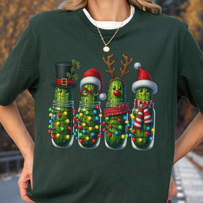 May include: Dark green t-shirt featuring a festive design of four anthropomorphic pickles in glass jars, each adorned with Christmas decorations. The pickles wear a top hat, Santa hats, reindeer antlers, and a striped scarf, all illuminated by colorful string lights.