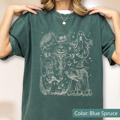 May include: Blue spruce-colored t-shirt with a Halloween-themed graphic. The design features a witch, ghosts, skulls, a scarecrow, and bats. The shirt is a comfortable, casual style.