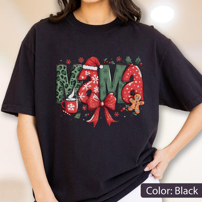 May include: Black t-shirt with a festive "MAMA" design. The letters feature a mix of patterns, including leopard print, snowflakes, and polka dots. A red bow and gingerbread man add to the holiday theme.