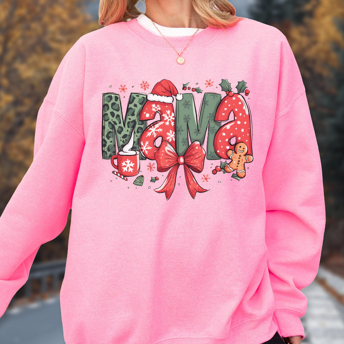 May include: Pink sweatshirt with the word "MAMA" in a festive Christmas design. The letters feature leopard print, snowflakes, and a Santa hat. A red bow and gingerbread man complete the holiday theme.