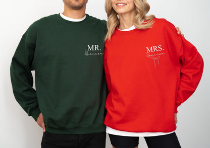 May include: Matching green and red sweatshirts. The green sweatshirt has "MR. Spencer" printed on the front. The red sweatshirt has "MRS. Spencer" printed on the front. Both sweatshirts have a white crew neck collar.