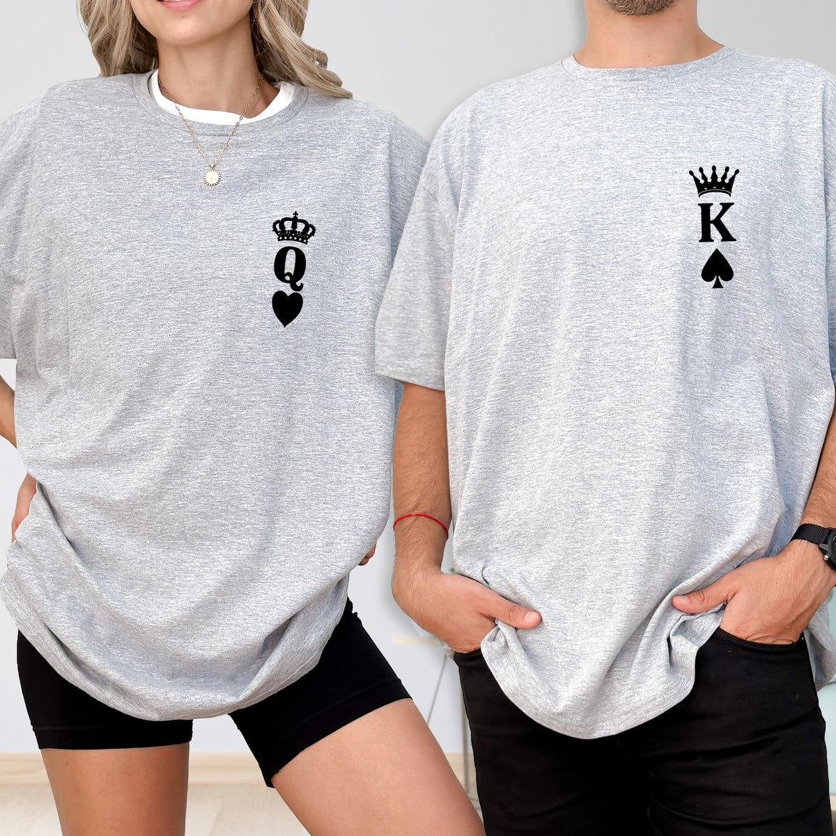 May include: Two gray t-shirts, one with a black Queen of Hearts design and the other with a black King of Spades design. The shirts are short-sleeved and have a relaxed fit. The Queen shirt is worn with black shorts, and the King shirt is worn with black pants.