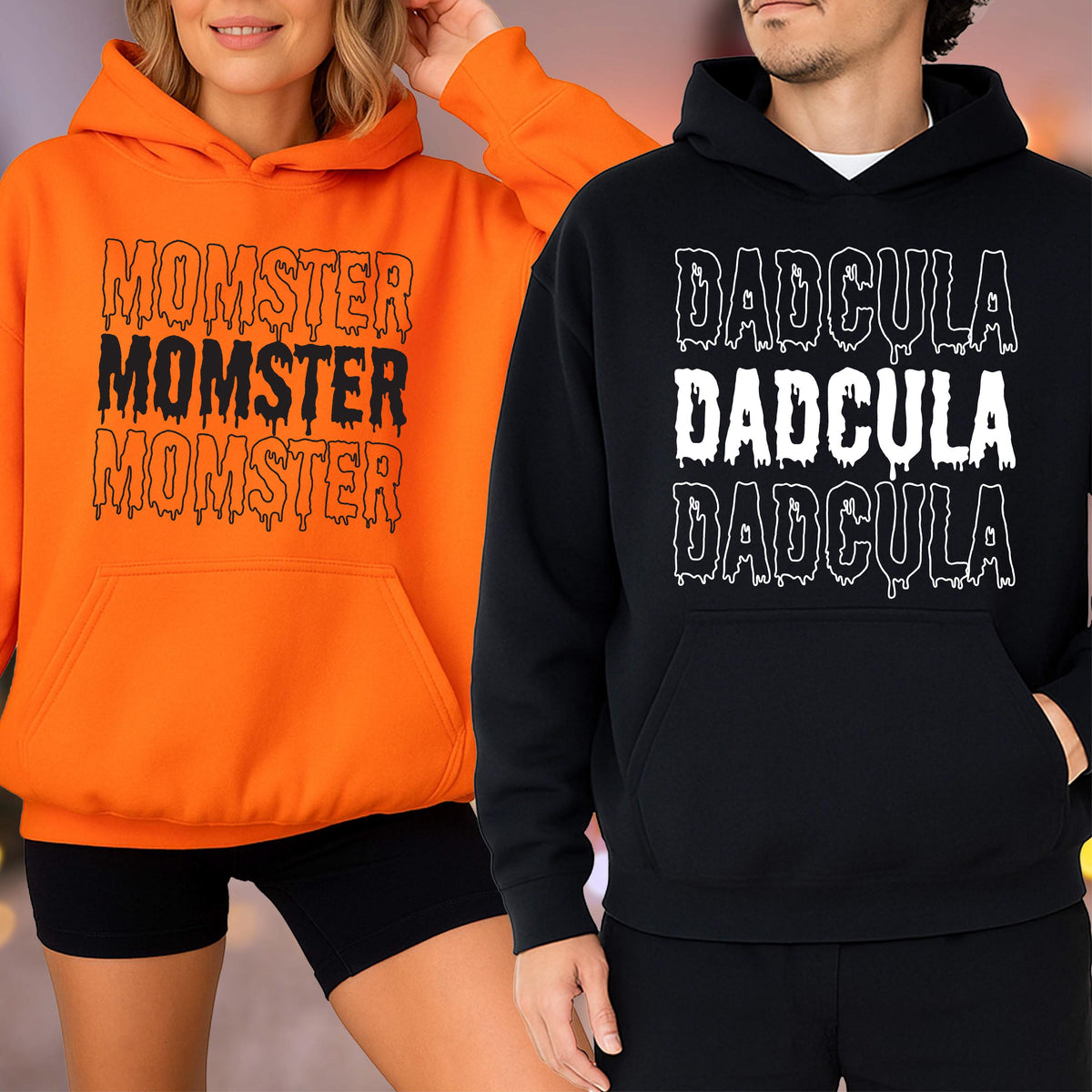 May include: Two hooded sweatshirts, one orange and one black. The orange sweatshirt has the text "MOMSTER MOMSTER MOMSTER" in black dripping font. The black sweatshirt has the text "DADGULA DADGULA DADGULA" in white dripping font.