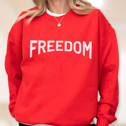 May include: A red sweatshirt with the word "FREEDOM" printed in large, white capital letters across the chest. The sweatshirt is a solid red color and appears to be made of a soft material.