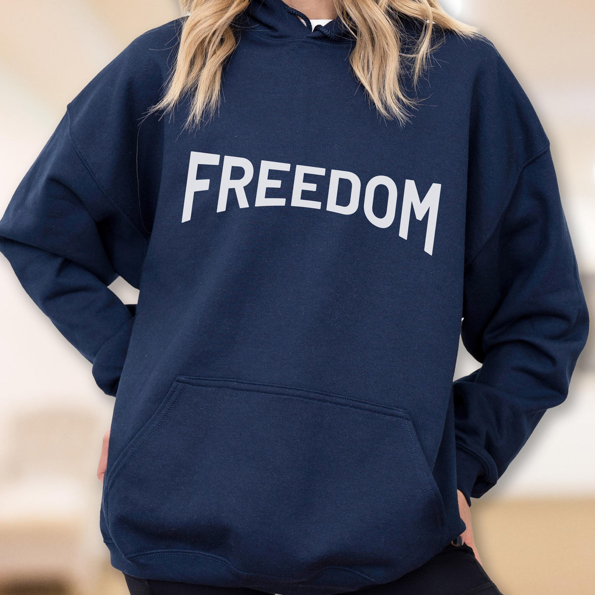 May include: Navy blue hoodie with the word "FREEDOM" printed in large, white capital letters across the chest. The hoodie features a front pocket and a hood with a drawstring. The overall design is simple and bold.