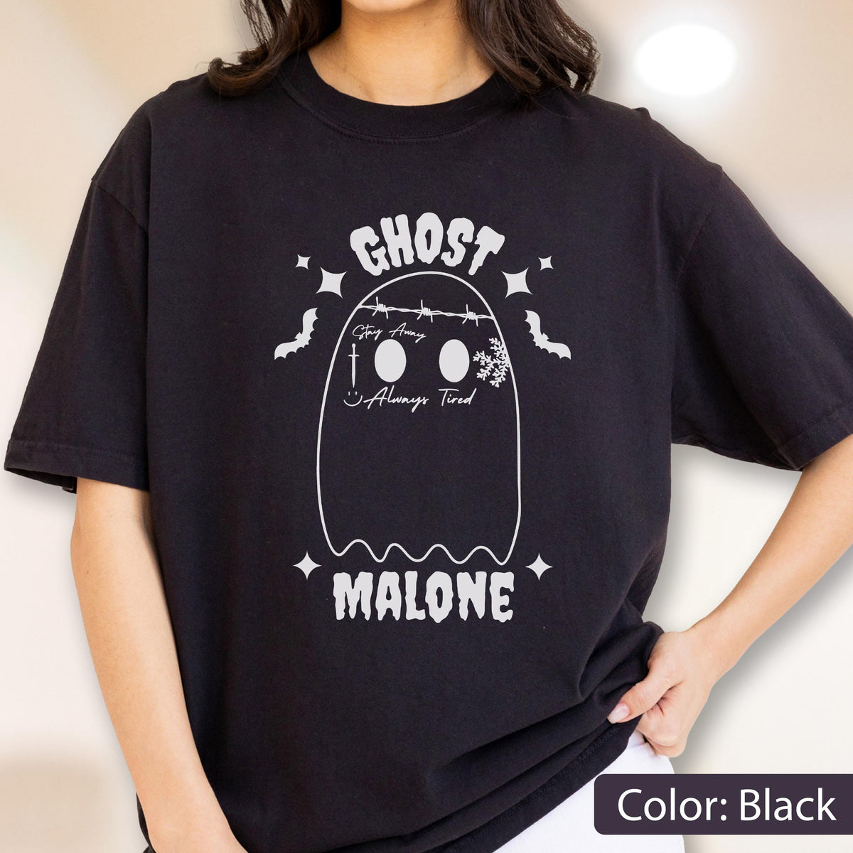 May include: Black t-shirt with a white ghost graphic. The ghost design includes the text "GHOST" above the ghost, and "MALONE" below. The ghost has the text "Stay Away" and "Always Tired" on it. The design also includes bats and stars.