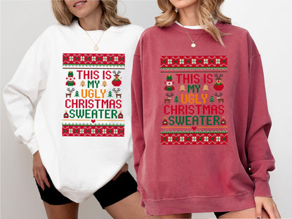 May include: Two sweatshirts, one white and one burgundy, feature a festive design. The design includes the text "THIS IS MY UGLY CHRISTMAS SWEATER" with holiday-themed graphics like a snowman, reindeer, and bells. The sweatshirts are a comfortable, casual style.