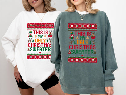 May include: Two sweatshirts, one white and one teal, feature a festive design. The design includes the text "THIS IS MY UGLY CHRISTMAS SWEATER" in a colorful, pixelated style, with holiday icons like a nutcracker, bells, and reindeer.
