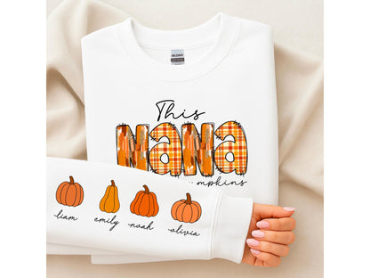 May include: White sweatshirt with the text "This NANA" in a plaid design, with the word "pumpkins" below. The sleeve features pumpkin illustrations and names: Liam, Emily, Noah, and Olivia.