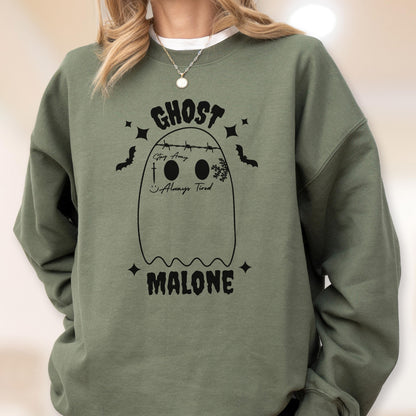 May include: An olive green sweatshirt with a black ghost graphic. The ghost design includes the word "GHOST" above the ghost, and the word "MALONE" below. The ghost has two eyes, a smile, and the text "Stay Away" and "Always Tired".