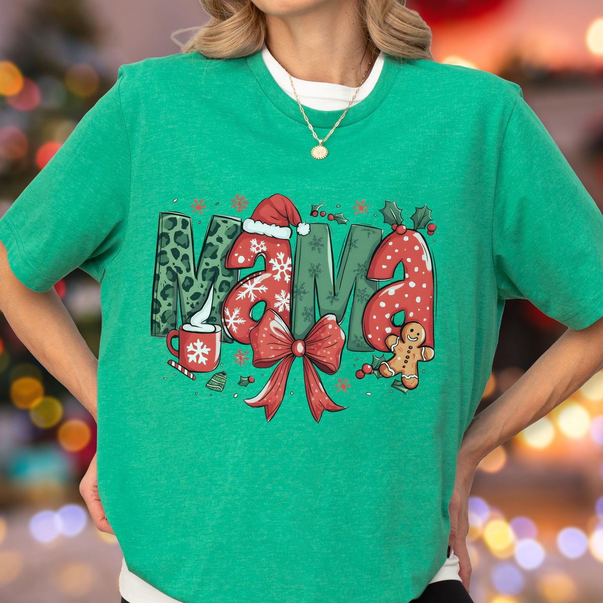 May include: Green Christmas-themed t-shirt with the word "Mama" in a festive design. The letters feature leopard print, snowflakes, and a Santa hat. A red bow, gingerbread man, and holly complete the holiday look.