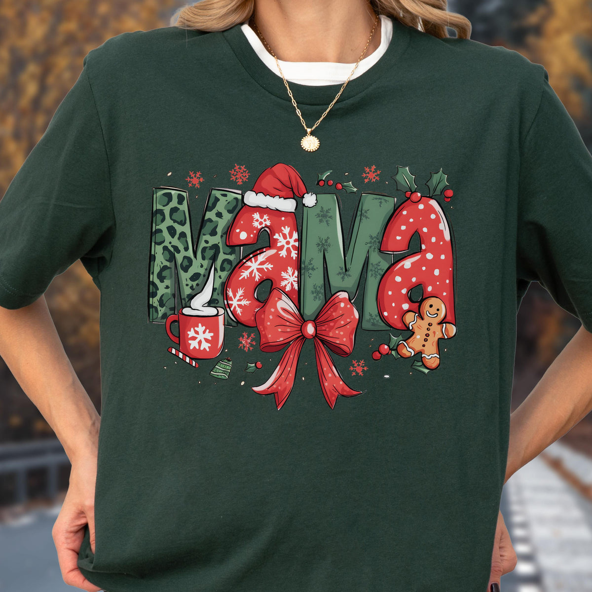 May include: Dark green t-shirt with the word "MAMA" in festive Christmas-themed letters. The "M" has a leopard print pattern, the "A"s are red with white polka dots, and the design includes a red bow, gingerbread man, and snowflakes.